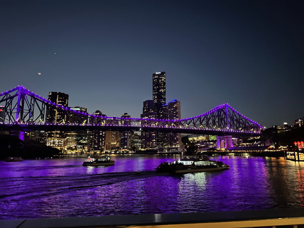 View of the Story Bridge in Brisbane at night, illuminated against the city skyline.